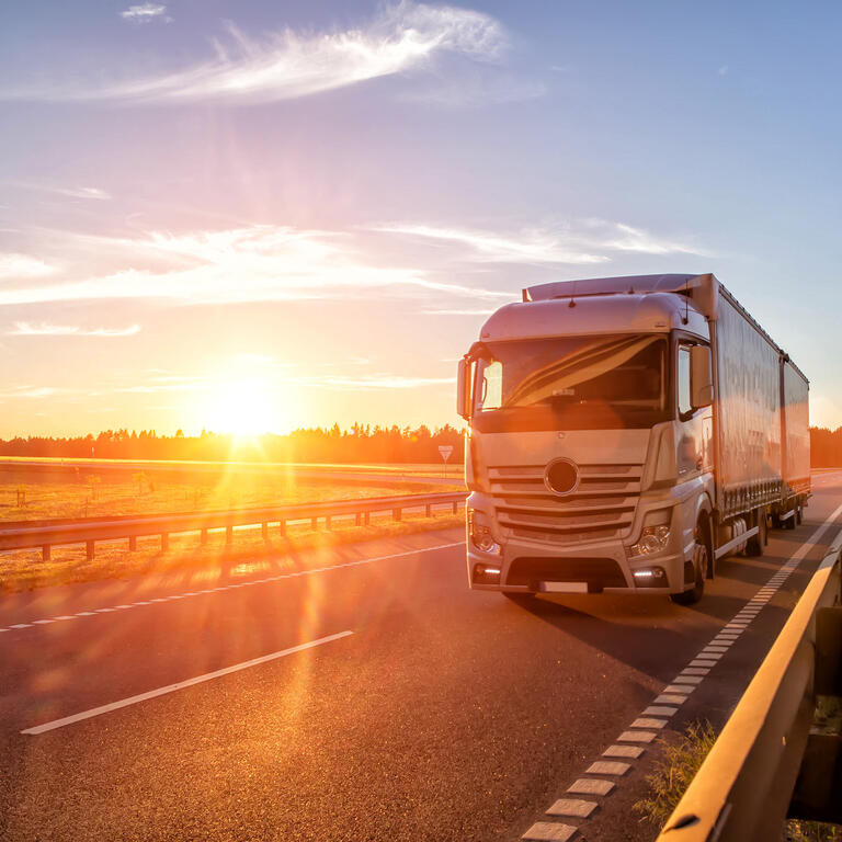 Modern wagon truck transports cargo against the backdrop of a sunset