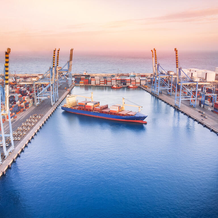 Large container ship leaves cargo port at sea, sunset. Aerial top view