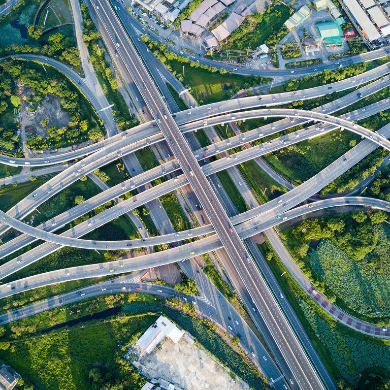 Aerial view of road interchange or highway intersection with busy urban traffic speeding on the road.