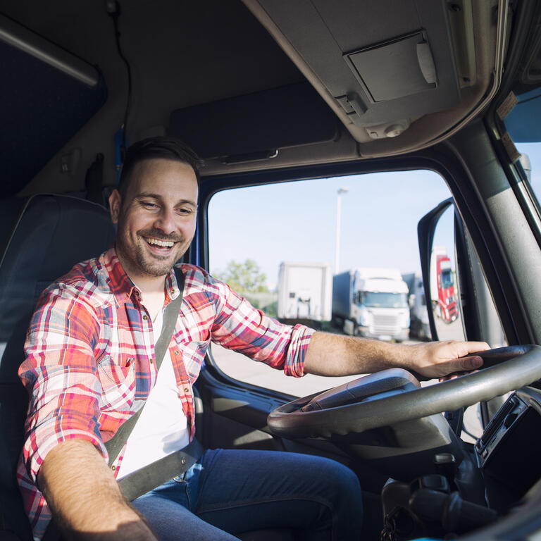 Truck driver driving his truck and changing radio station to play his favorite music. Trucker enjoying his job. Transportation services.