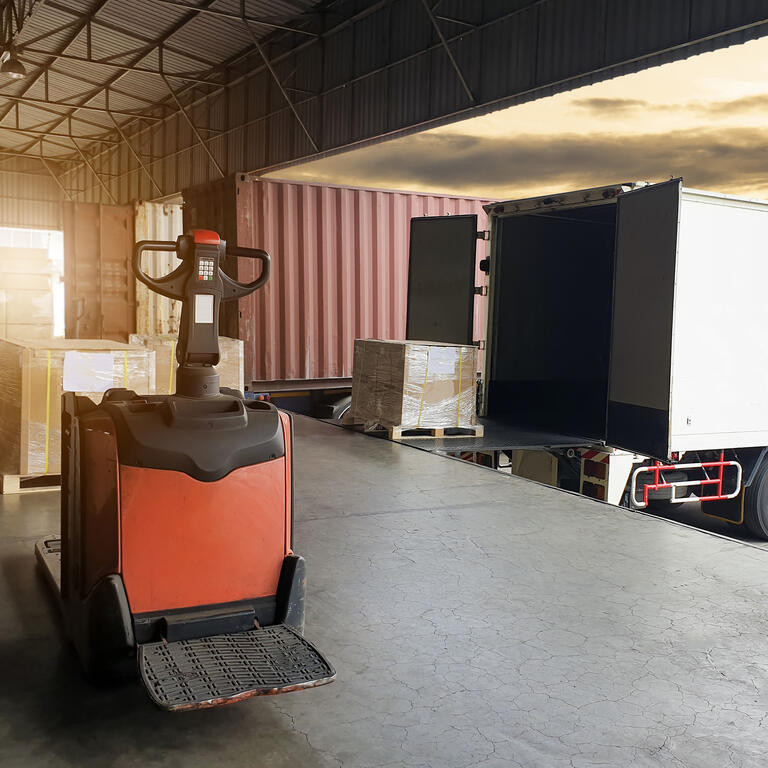 Truck container docking load shipment goods at warehouse, forklift pallet jack with stack package boxes on pallet, road freight industry delivery logistics