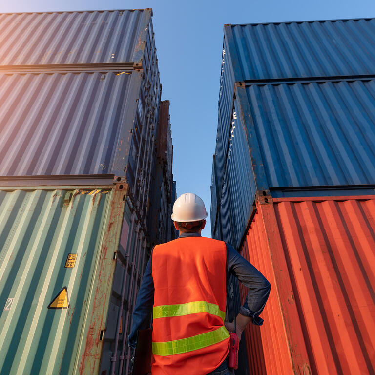 The abstract image of the engineer standing in shipping container yard and copy space. the concept of engineering, shipping, shipyard, business and transportations.