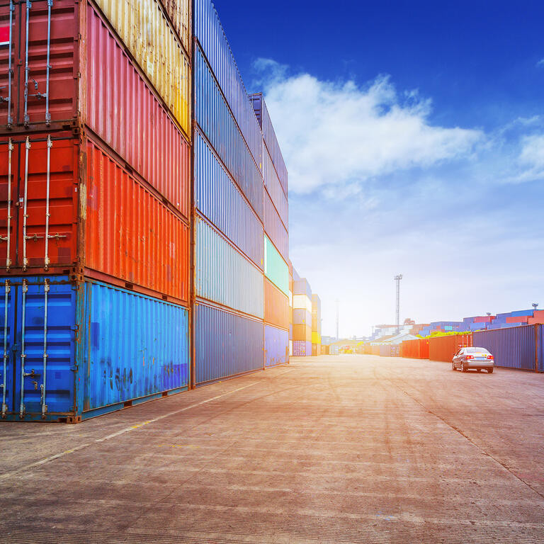 Empty road and containers in harbor at sunset