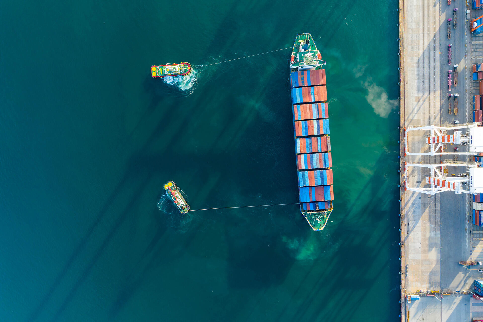 Aerial view. Container ship in pier with crane bridge carries out export and import business in the open sea