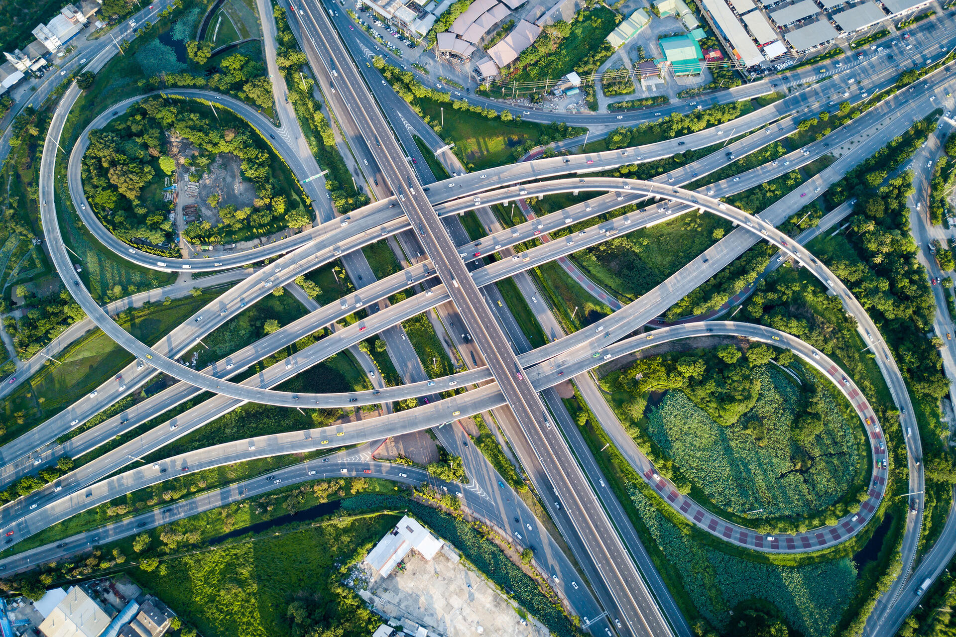 Aerial view of road interchange or highway intersection with busy urban traffic speeding on the road.